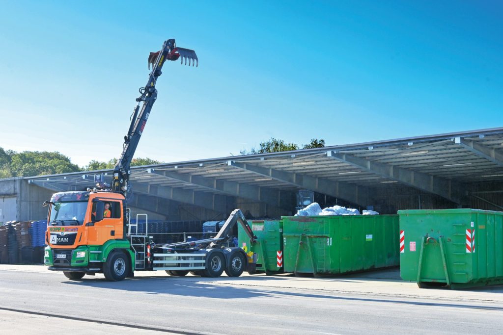 A crane is lifting a container onto a truck