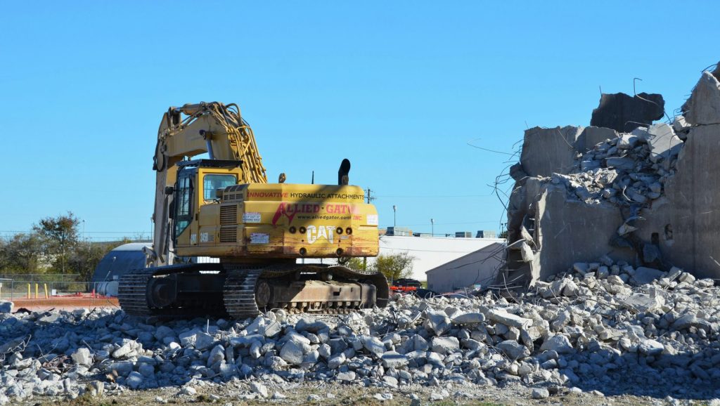Yellow excavator demolishing concrete structure